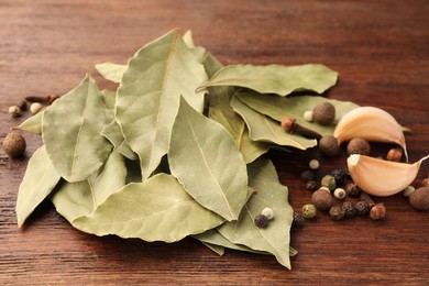 Photo of Aromatic bay leaves and spices on wooden table, closeup