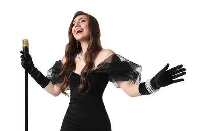 Beautiful young woman in stylish black dress with microphone singing on white background