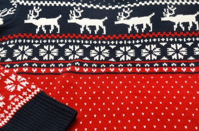 Photo of Warm Christmas sweater with deer as background, closeup view