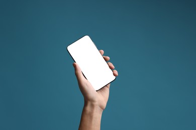 Photo of Man holding smartphone with blank screen on light blue background, closeup. Mockup for design