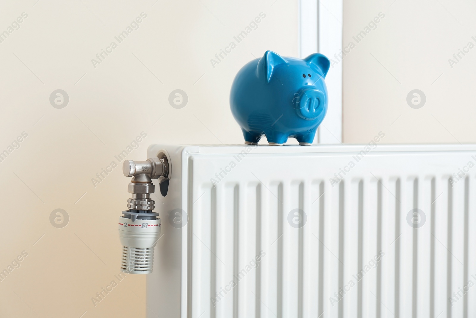 Photo of Piggy bank on modern heating radiator indoors