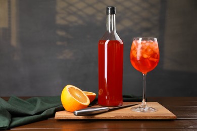 Photo of Aperol spritz cocktail and ice cubes in glass and bottle on wooden table