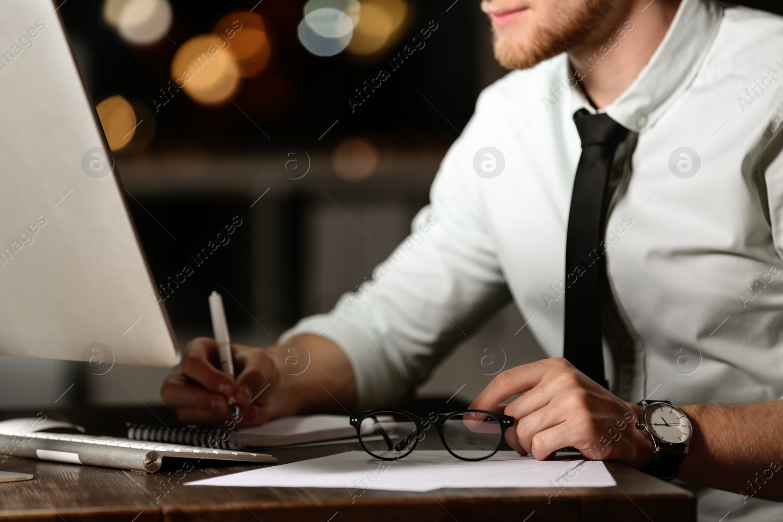 Photo of Young man working in office at night, closeup