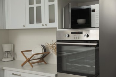 Photo of Modern microwave oven on shelf in kitchen