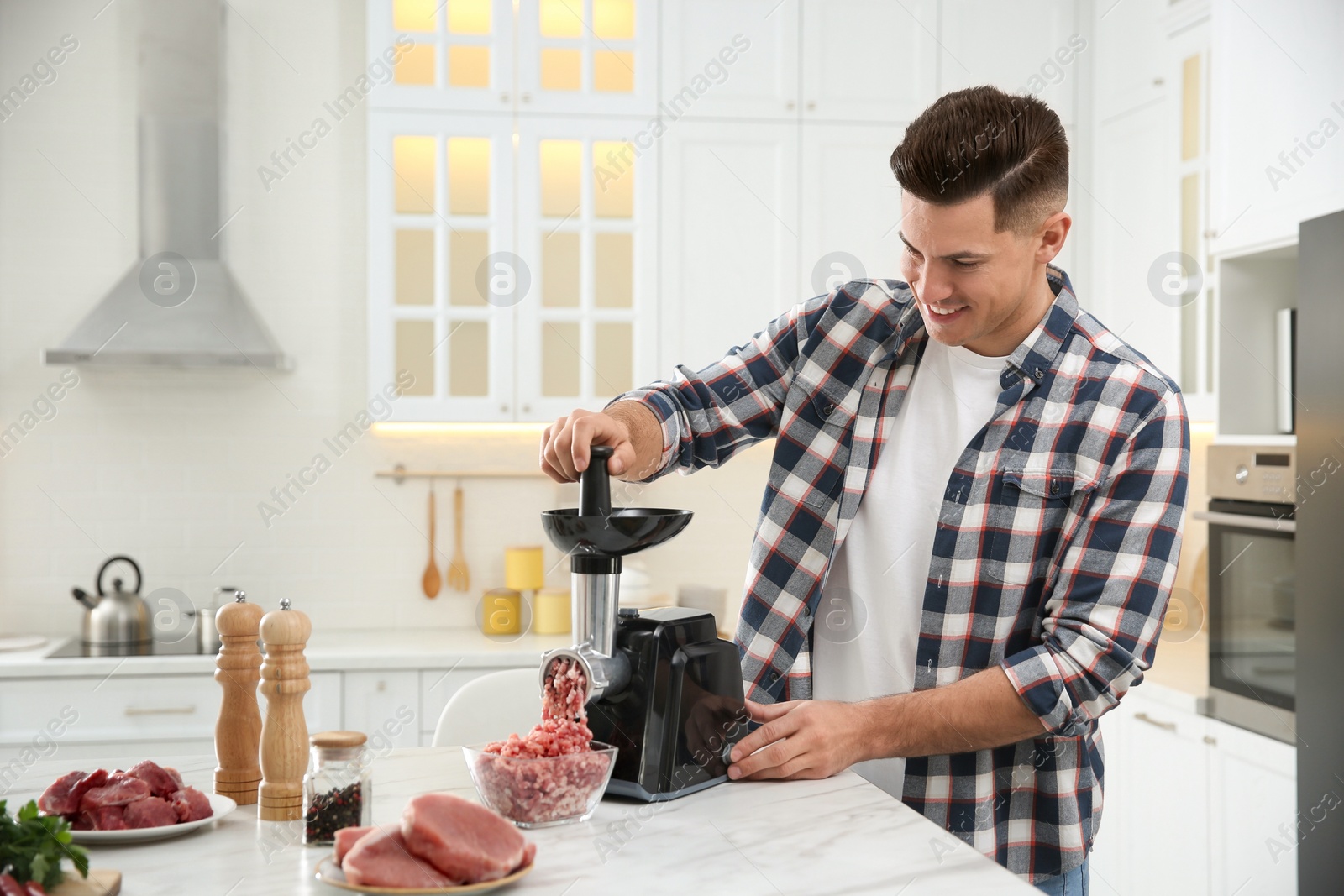 Photo of Man using modern meat grinder in kitchen