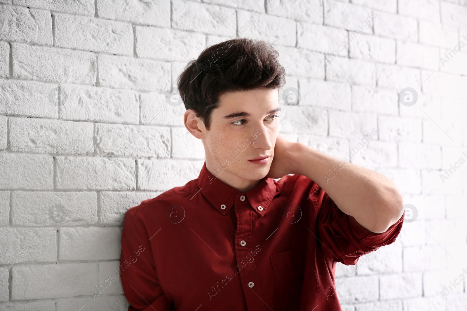 Photo of Portrait of young man with beautiful hair on brick wall background