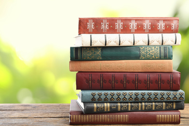 Collection of different books on wooden table against blurred green background, space for text
