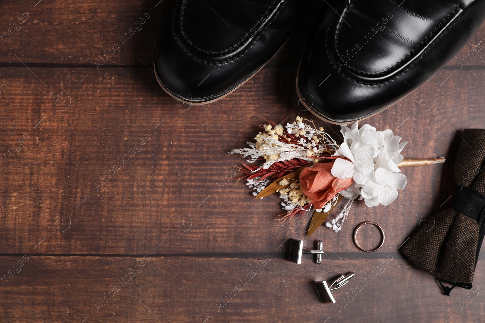 Photo of Wedding stuff. Flat lay composition with stylish boutonniere on wooden background, space for text