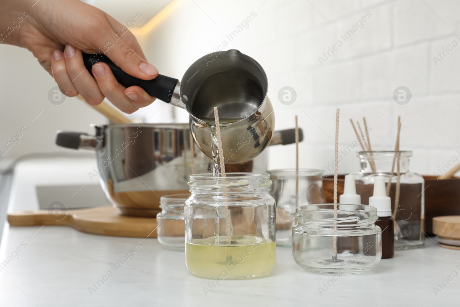 Photo of Woman making homemade candle at table in kitchen, closeup