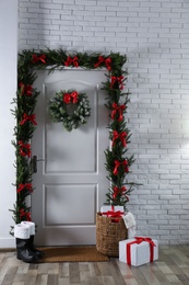 Photo of Stylish hallway interior with decorated door and Christmas gifts