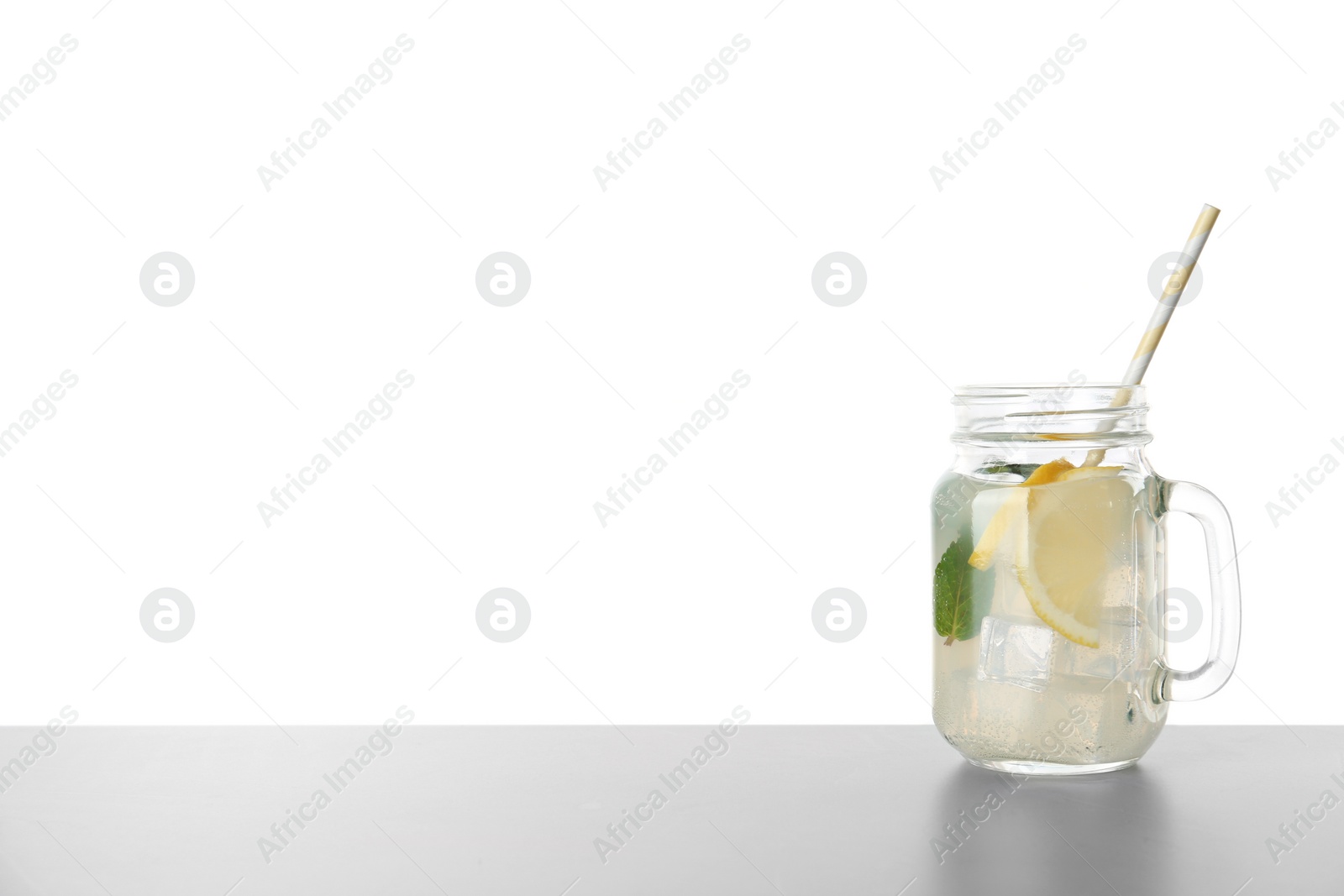 Photo of Delicious lemonade in mason jar on grey table against white background. Space for text