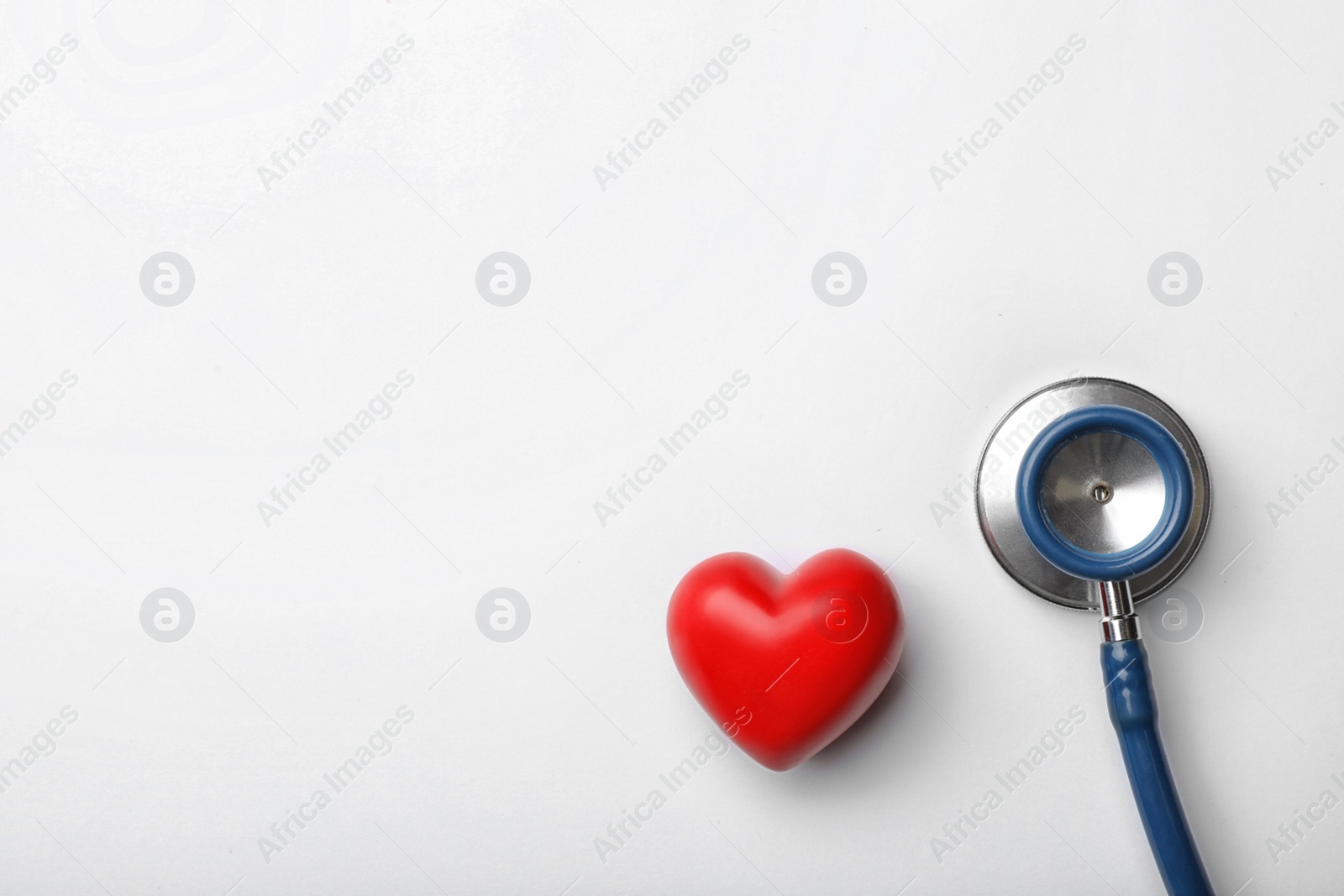Photo of Stethoscope for checking pulse and red heart on white background, top view. Space for text