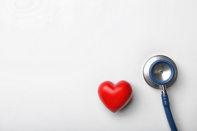 Photo of Stethoscope for checking pulse and red heart on white background, top view. Space for text