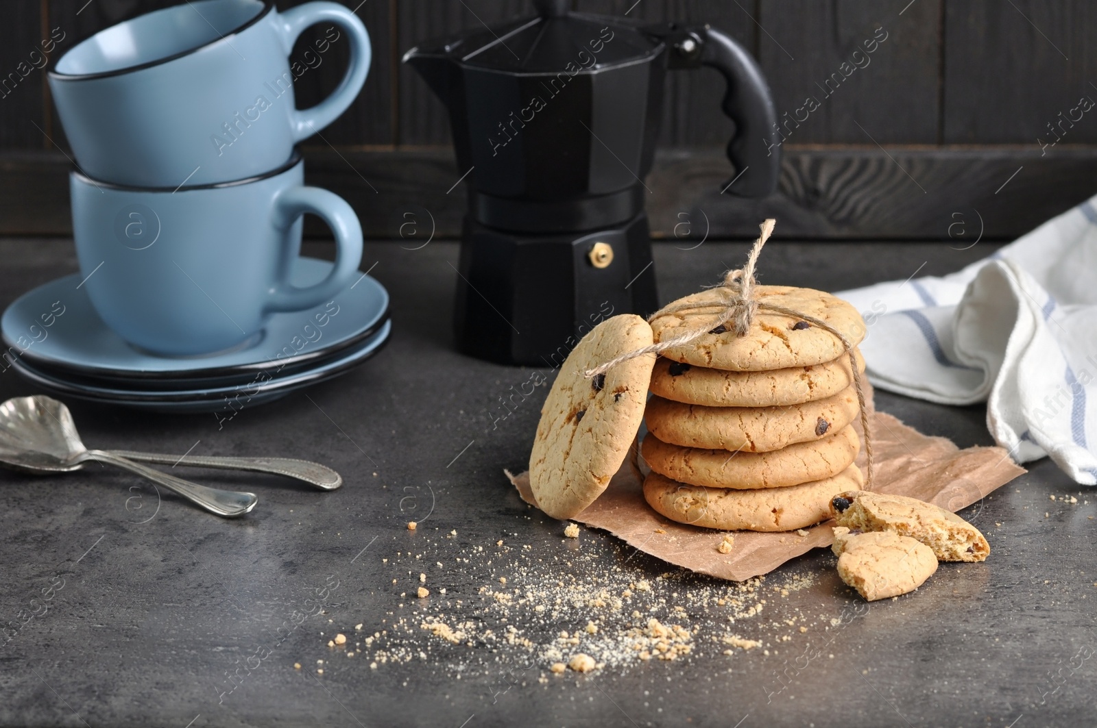 Photo of Tasty homemade cookies tied with rope near cups on grey table