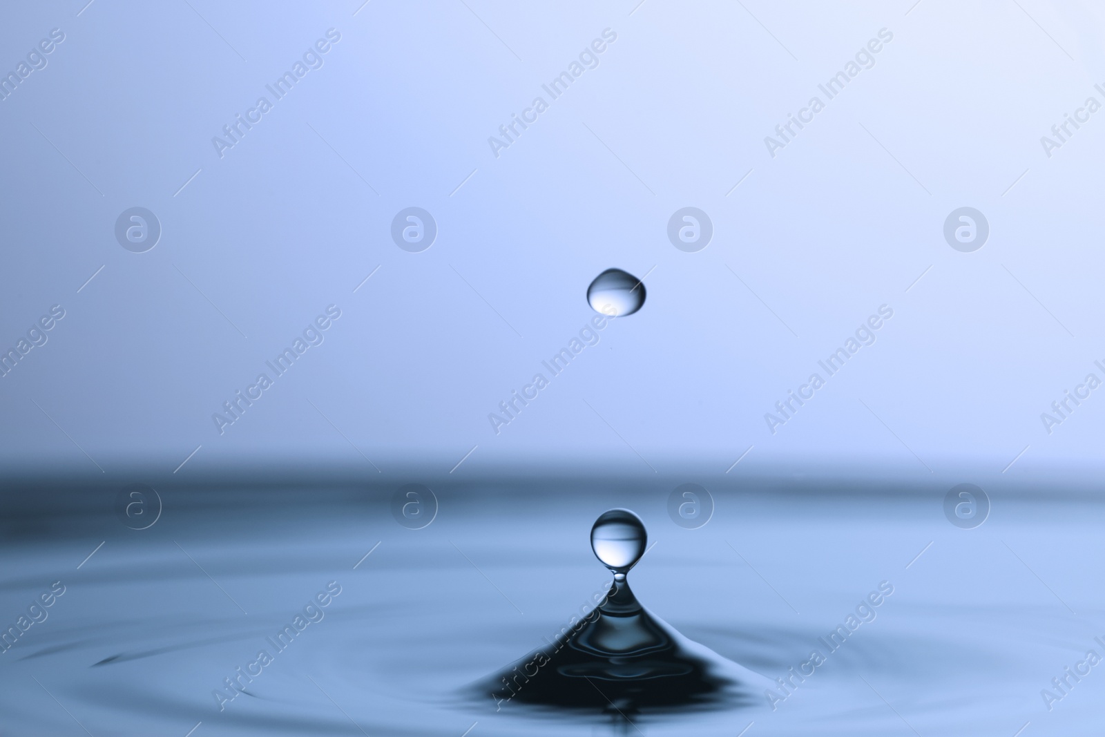 Photo of Splash of clear water with drops on light blue background, closeup