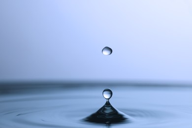 Photo of Splash of clear water with drops on light blue background, closeup