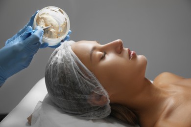 Photo of Cosmetologist applying mask on client's face in spa salon