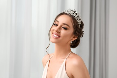 Photo of Beautiful young woman wearing luxurious tiara indoors, space for text