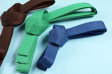 Photo of Colorful karate belts on light blue background, closeup
