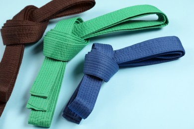 Colorful karate belts on light blue background, closeup