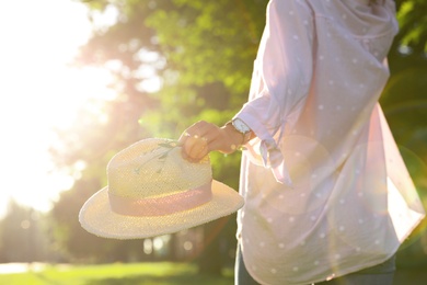 Photo of Young woman with straw hat and flowers outdoors on sunny day, closeup