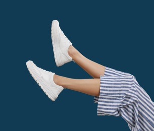 Photo of Woman in stylish sport shoes on blue background