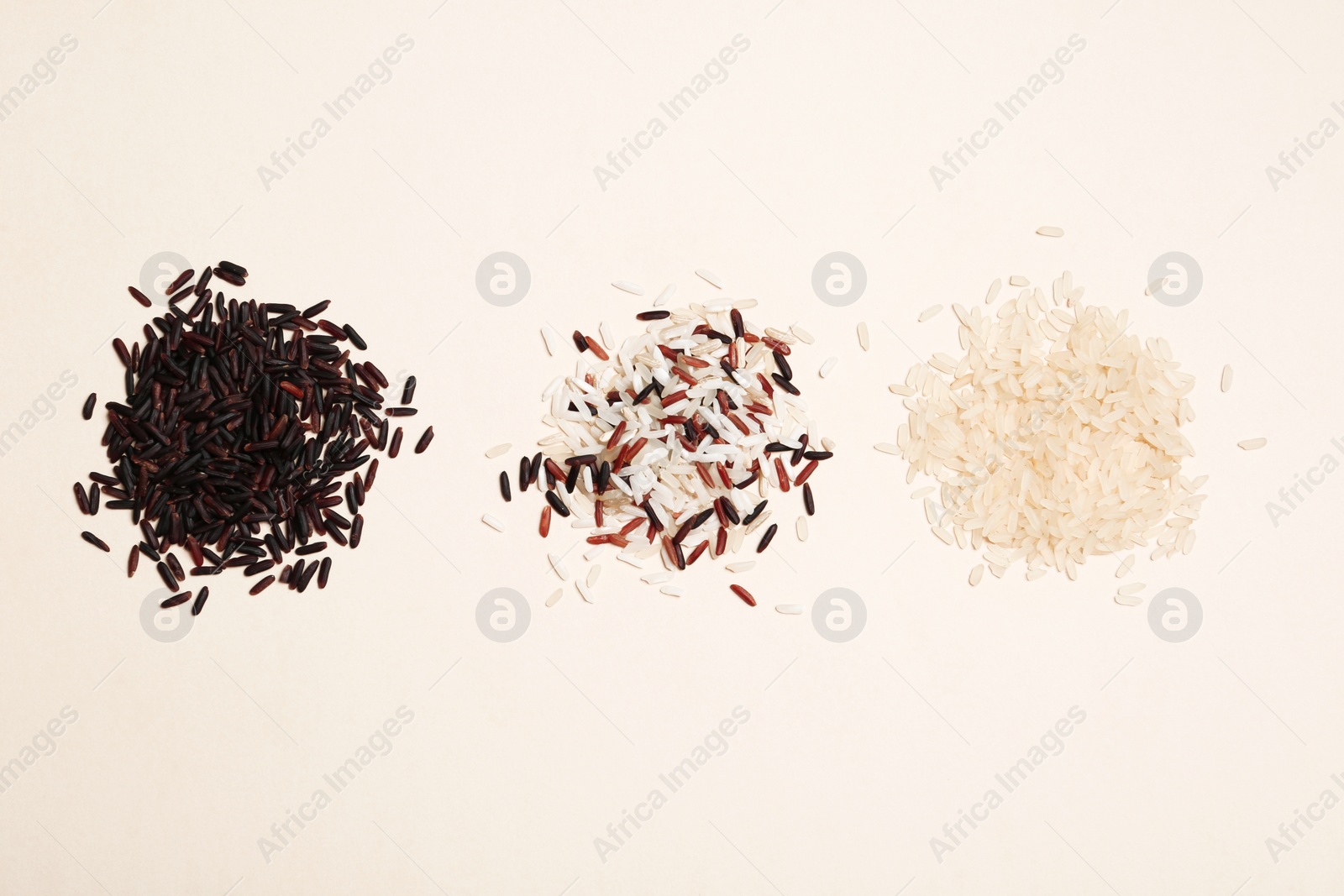 Photo of Brown and other types of rice on light background, top view