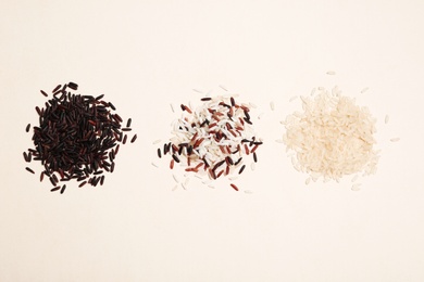 Brown and other types of rice on light background, top view