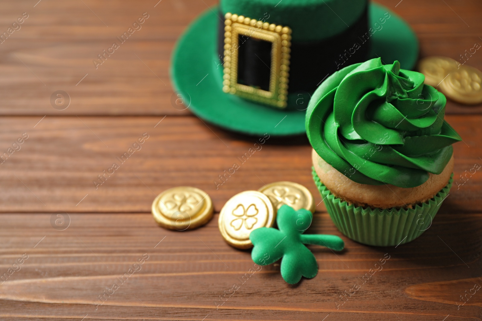 Photo of Composition with delicious decorated cupcake on wooden table. St. Patrick's Day celebration