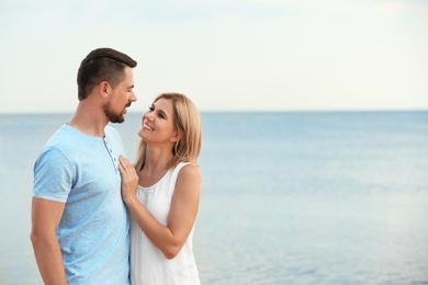 Photo of Happy romantic couple spending time together on beach, space for text