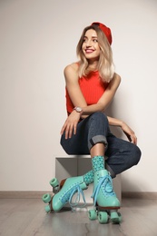 Photo of Young woman with retro roller skates against light wall