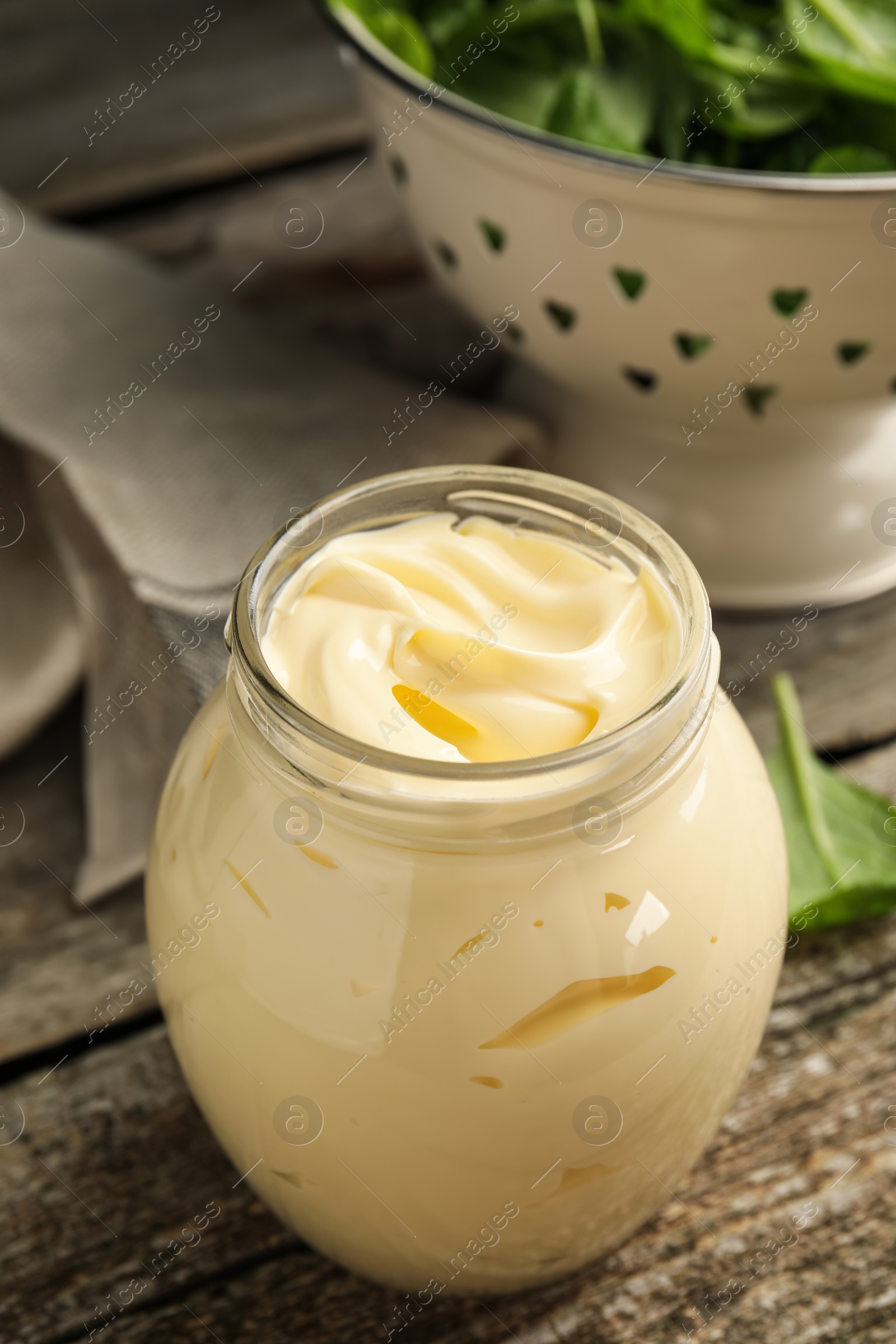 Photo of Jar of delicious mayonnaise and fresh spinach on wooden table