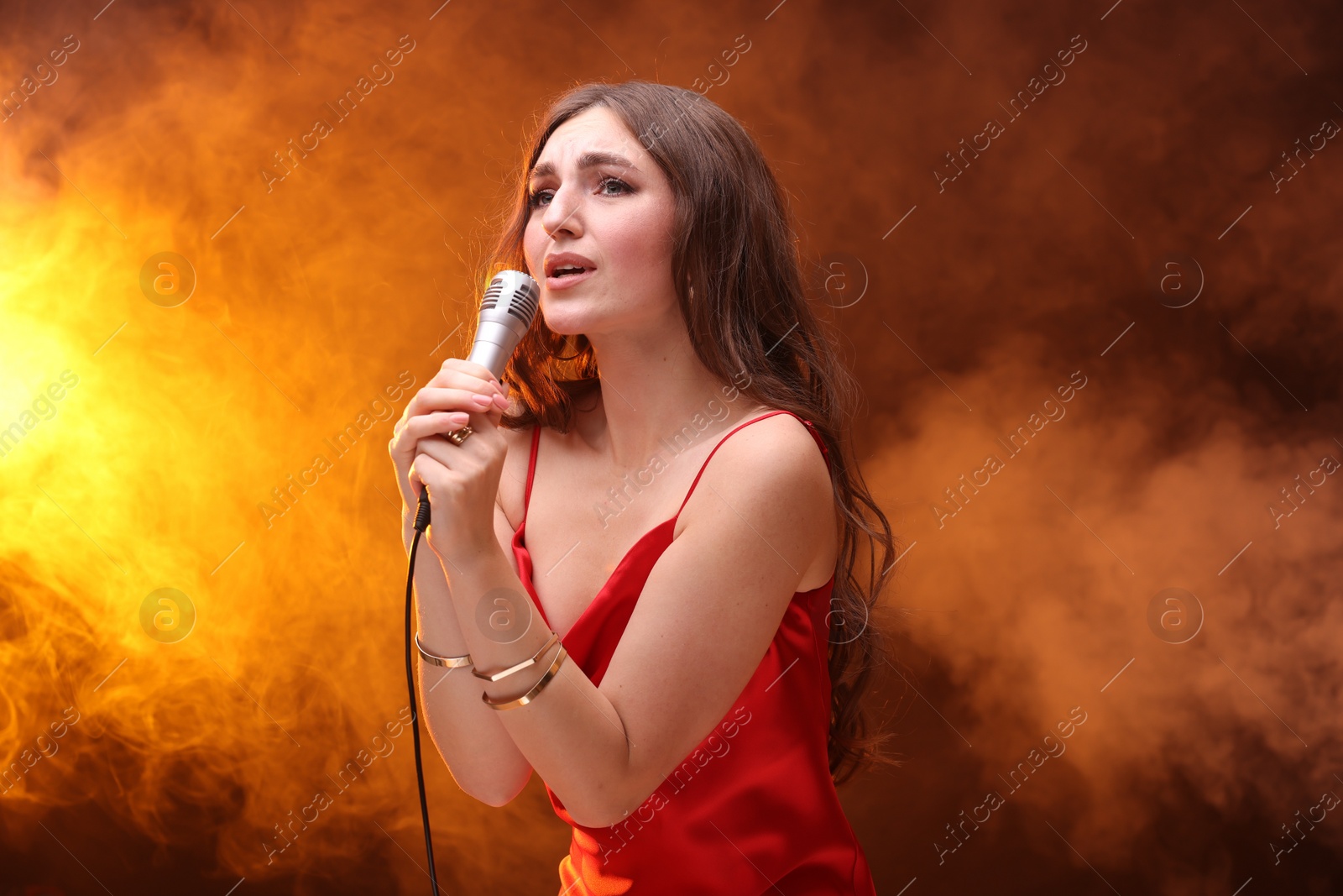Photo of Emotional woman with microphone singing in color light