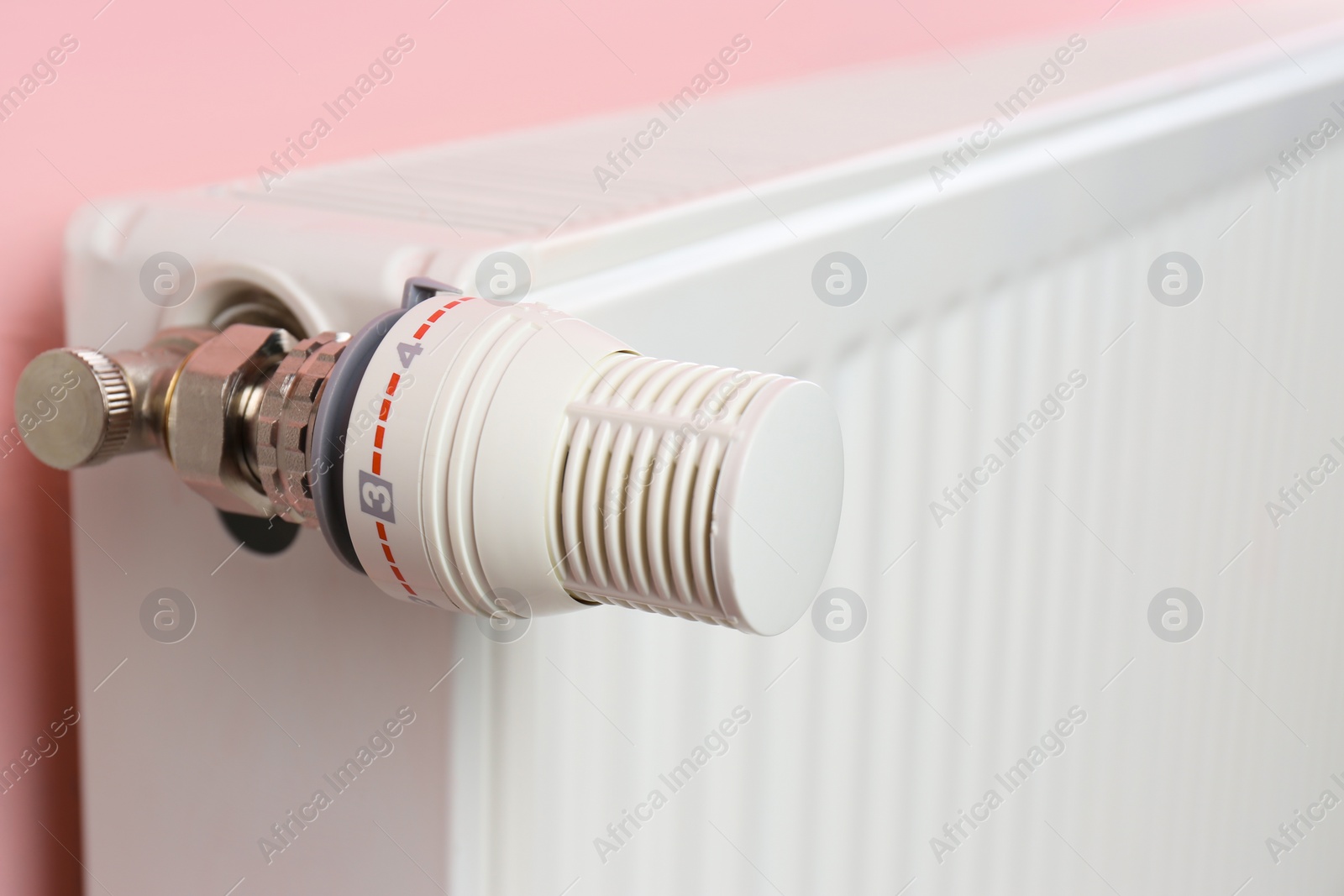 Photo of Heating radiator with temperature adjuster on color wall