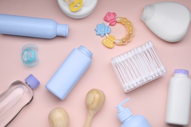 Photo of Different skin care products for baby, cotton buds, rattle and pacifier on light coral background, flat lay