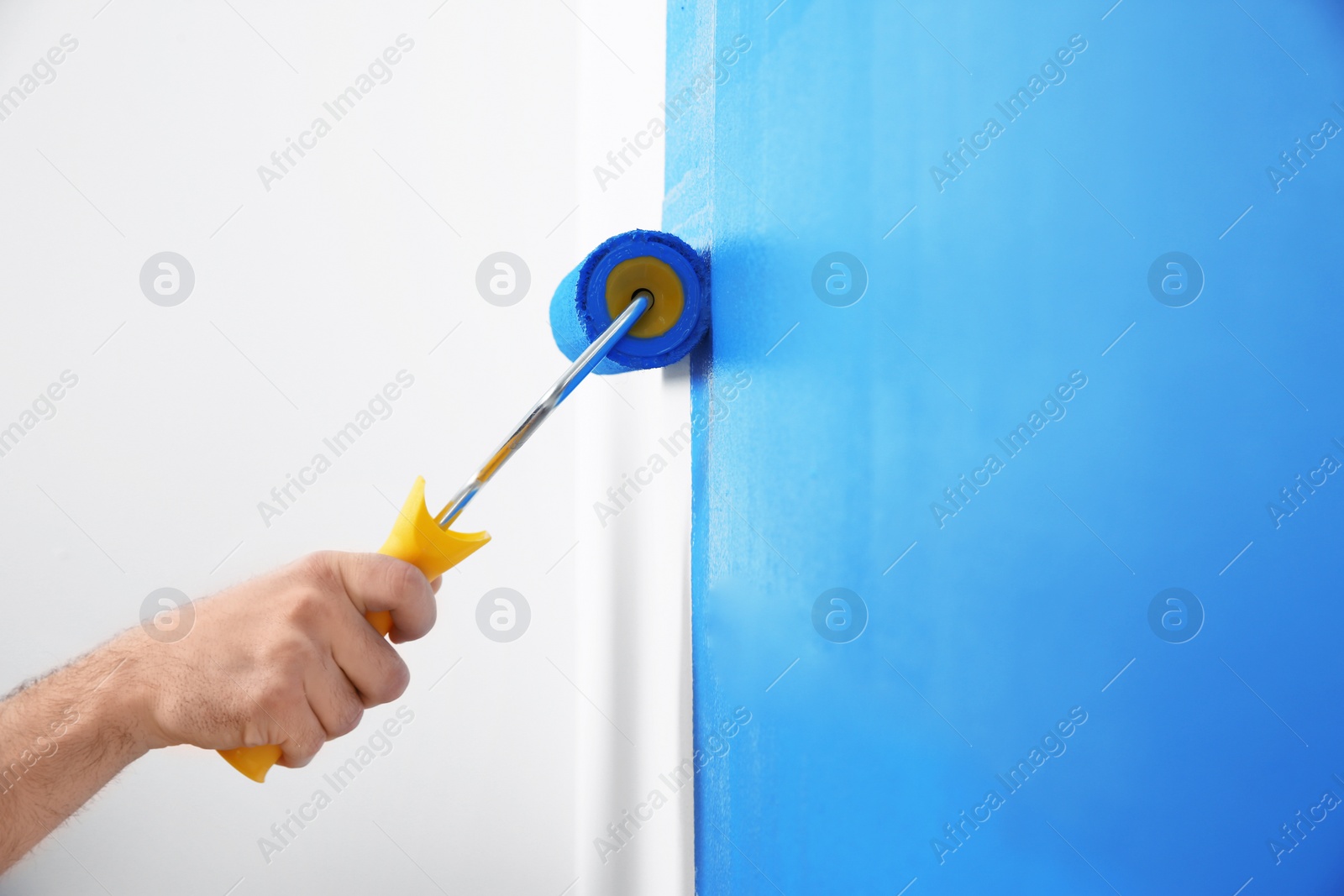 Photo of Man painting white wall with blue dye, closeup. Interior renovation