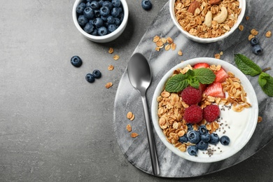 Healthy homemade granola with yogurt on grey table, flat lay. Space for text