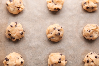 Photo of Cookie dough with chocolate chips on parchment, top view