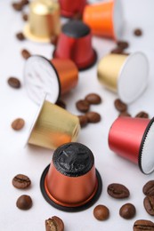 Photo of Many coffee capsules and beans on white table, closeup