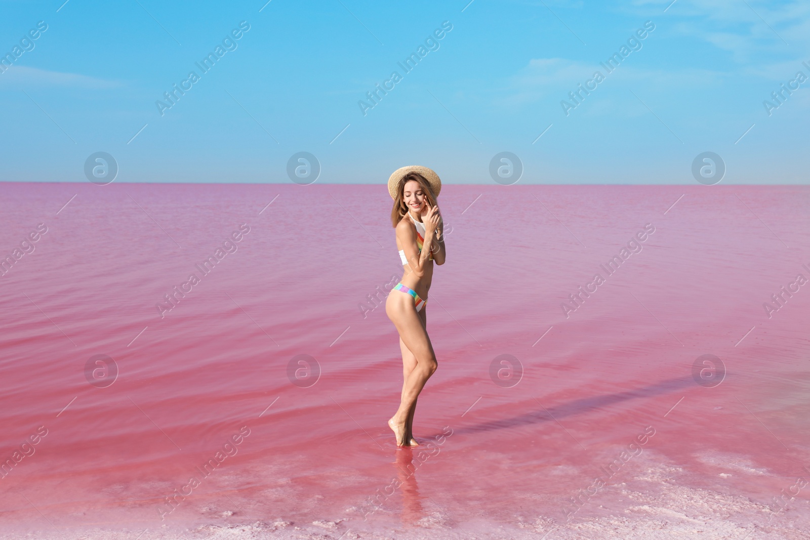 Photo of Beautiful woman in swimsuit posing near pink lake on sunny day