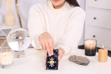 Soothsayer predicting future with tarot cards at table indoors, closeup