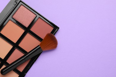 Photo of Colorful contouring palette and brush on violet background, top view with space for text. Professional cosmetic product