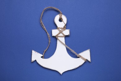 Photo of White wooden anchor figure on blue background, top view