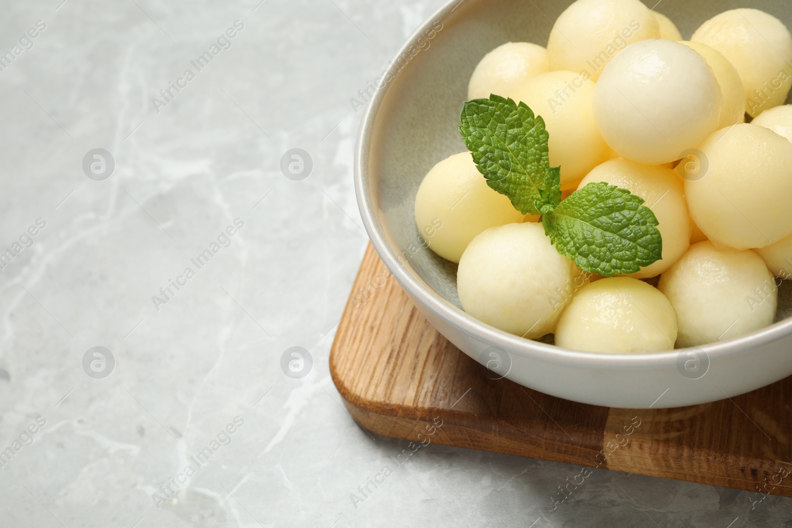 Photo of Melon balls with mint in bowl on grey table