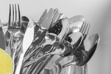 Photo of Washing silver spoons, forks and knives in water, closeup