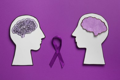 Human head cutouts with different brains and purple ribbon on color background, flat lay. Epilepsy awareness