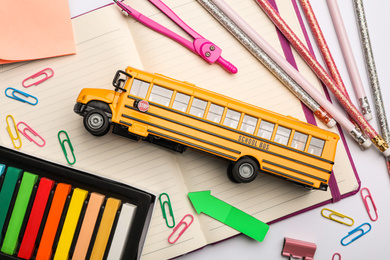 Photo of Flat lay composition with yellow school bus model on white background. Transport for students