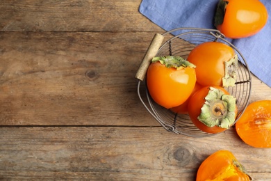 Photo of Delicious fresh persimmons on wooden table, flat lay. Space for text