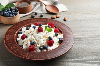 Fresh cottage cheese with berries and mint in plate on wooden table