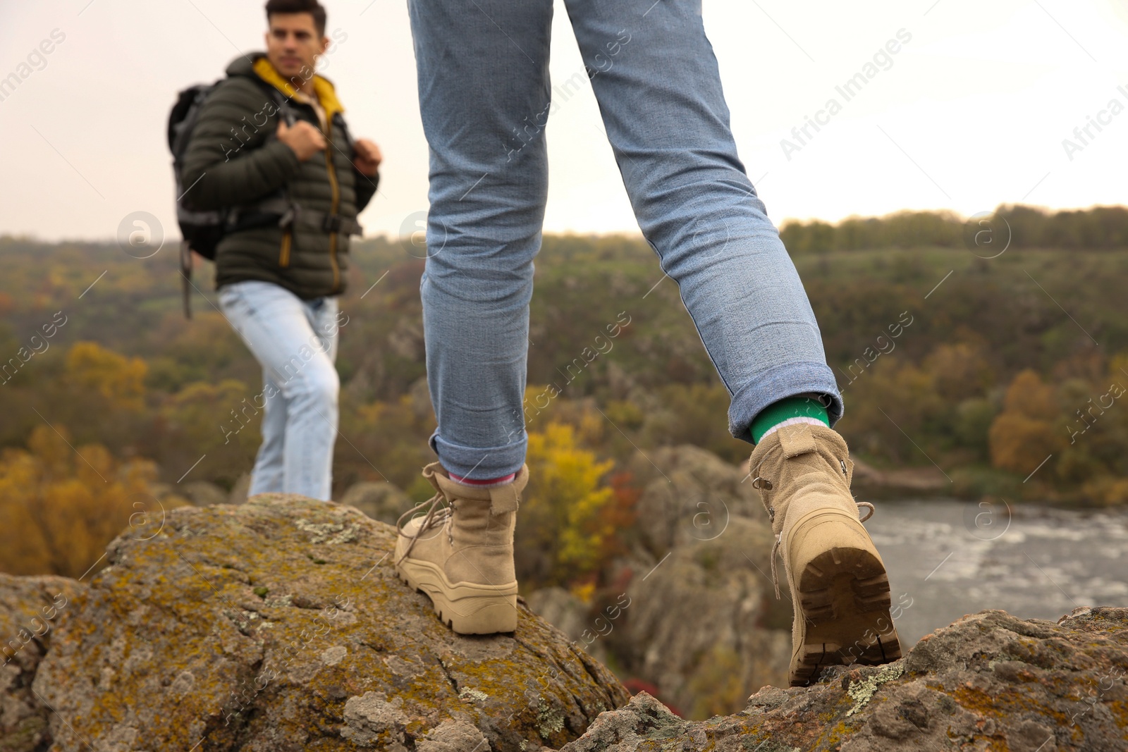 Photo of Couple of hikers with backpacks climbing up mountains, closeup